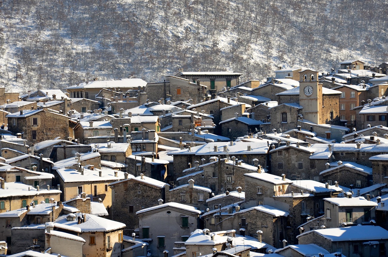 Borgo toscano incantevole con paesaggio invernale, case coperte di neve e alberi spogli.